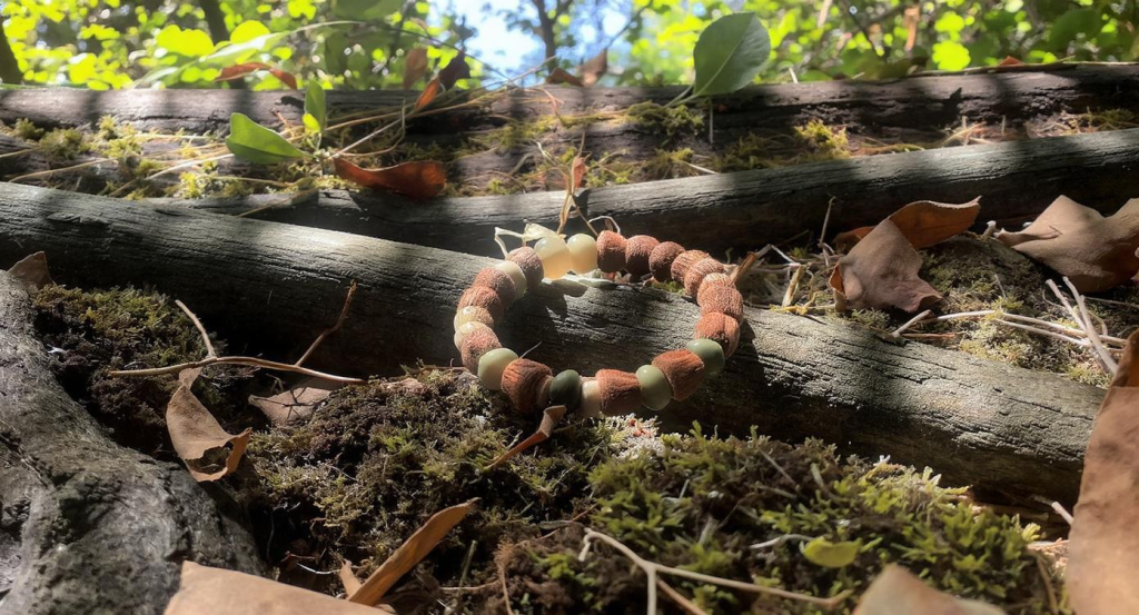 Macro shot of herbal bead bracelet with visible clove, agarwood, sandalwood textures, green background