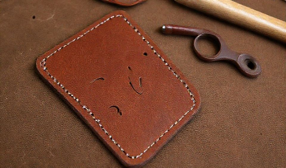 A modern leather workshop showing a blend of traditional tools like mallets and awls alongside a digital tablet displaying a design and a laser cutter in the background.