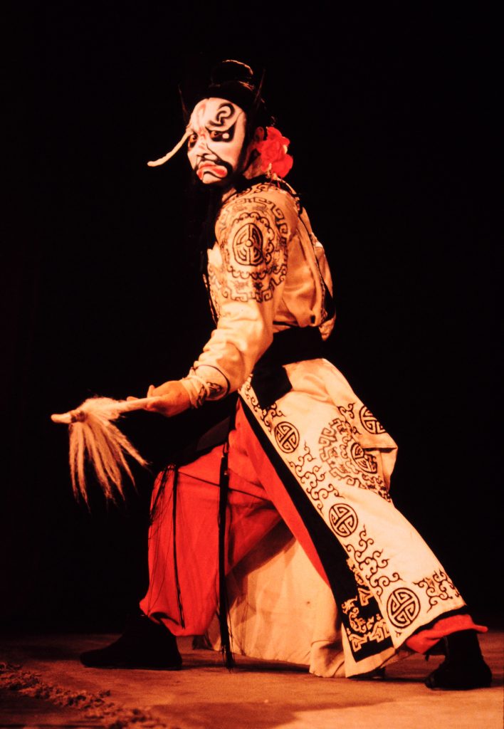 Peking opera performer in elaborate costume and makeup on stage - traditional Chinese theater