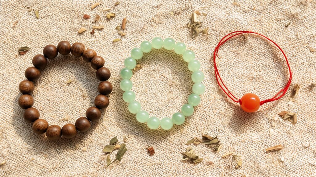 Flat-lay of Chinese herbal wellness bracelets with sandalwood, jade, and red string beads on natural linen